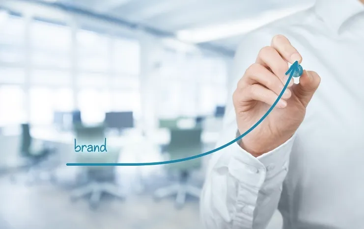 A professional drawing an upward trend line labeled "brand" symbolizing Trinergy's strategic approach to brand growth and development.
