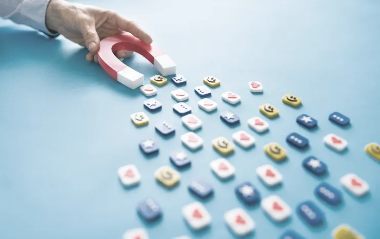A hand holding a magnet attracting social media icons, representing Trinergy's strategy for increasing digital engagement and audience growth.